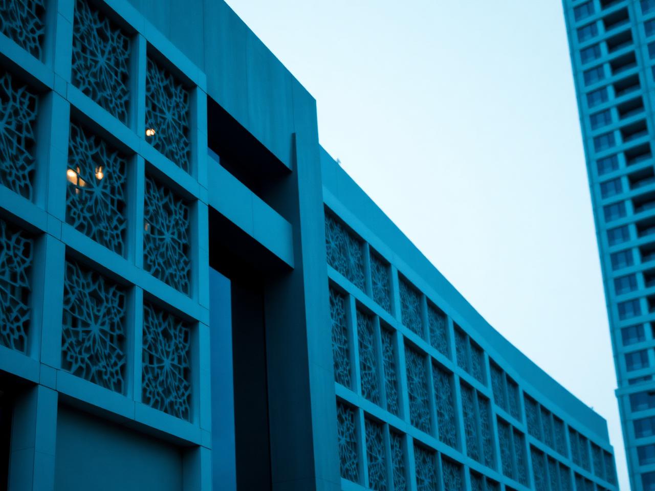 Contemporary Gulf business district facade with geometric sunshade detailing at dusk